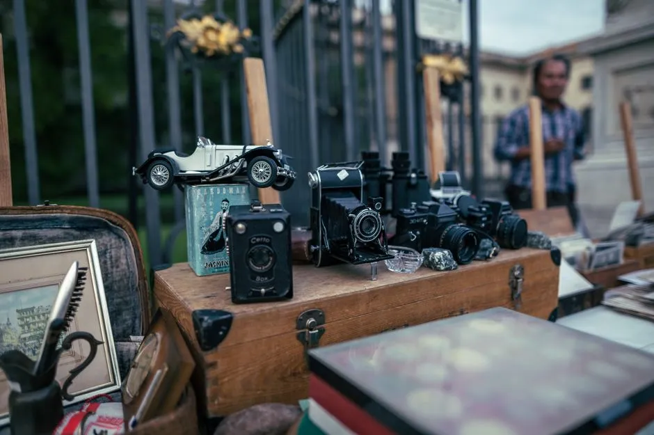Vintage cameras, a model car, and other collectibles laid out for sale on a table